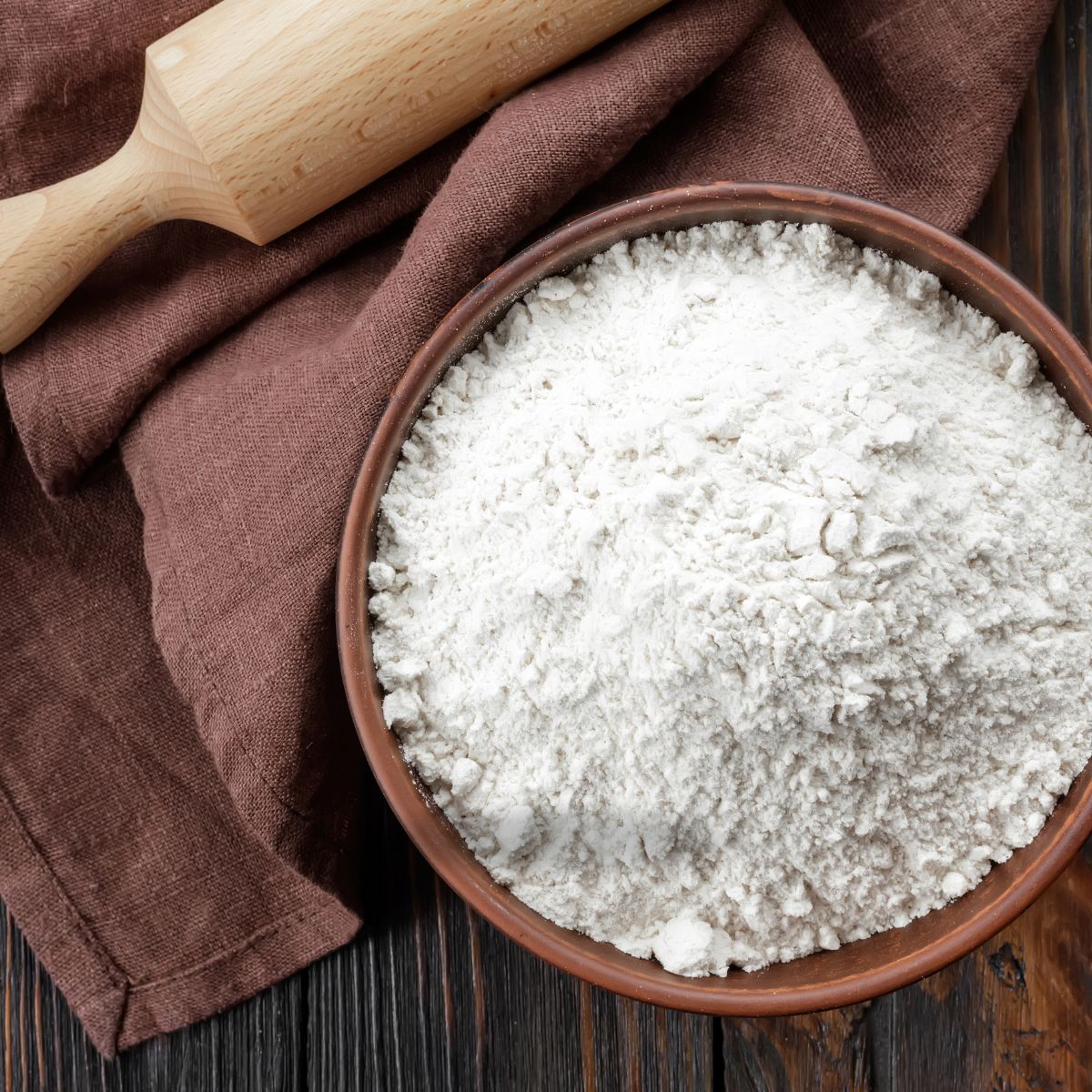 A wooden mixing bowl with flour.