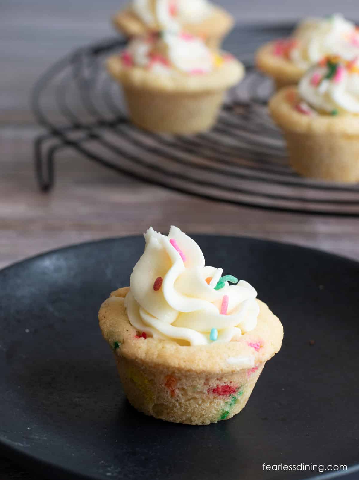 A gluten free funfetti cookie cup on a small black dessert plate.