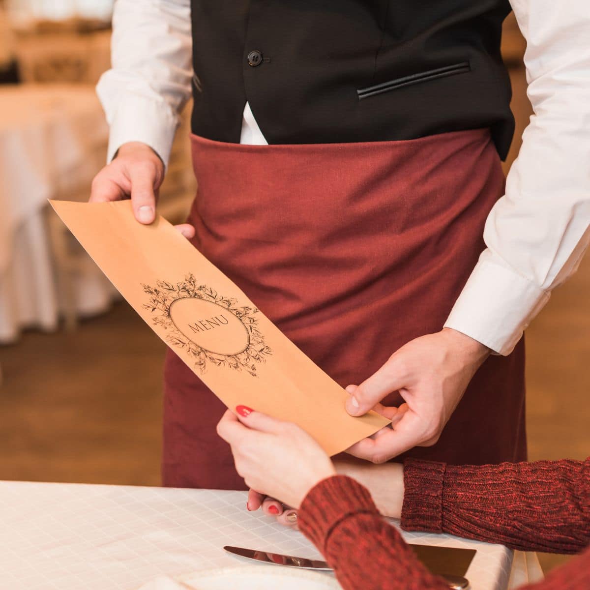 A waiter handing a menu to a customer in a restaurant.