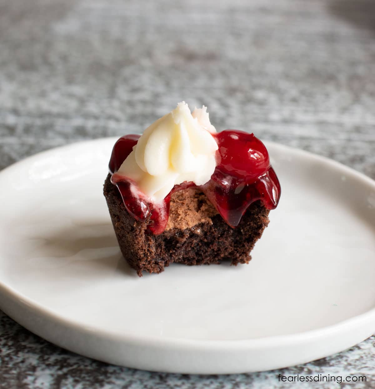 A single black forest cookie cup on a white plate with a bite taken out.