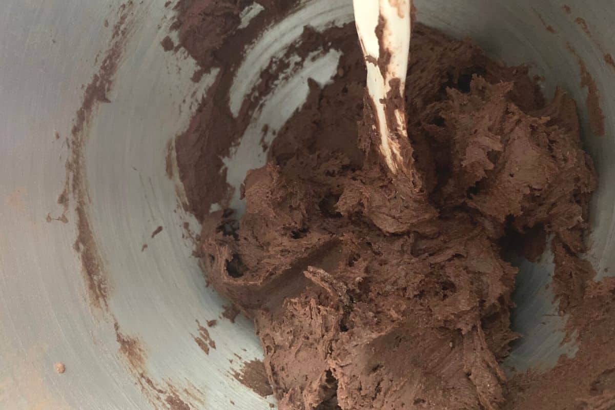 Chocolate cookie dough in a big silver mixing bowl.