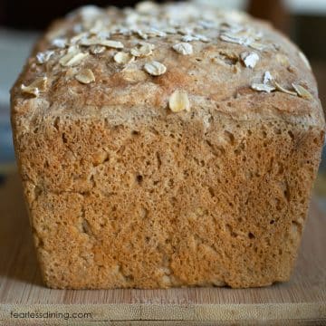 The front view of an unsliced loaf of gluten free oat bread on a cutting board.