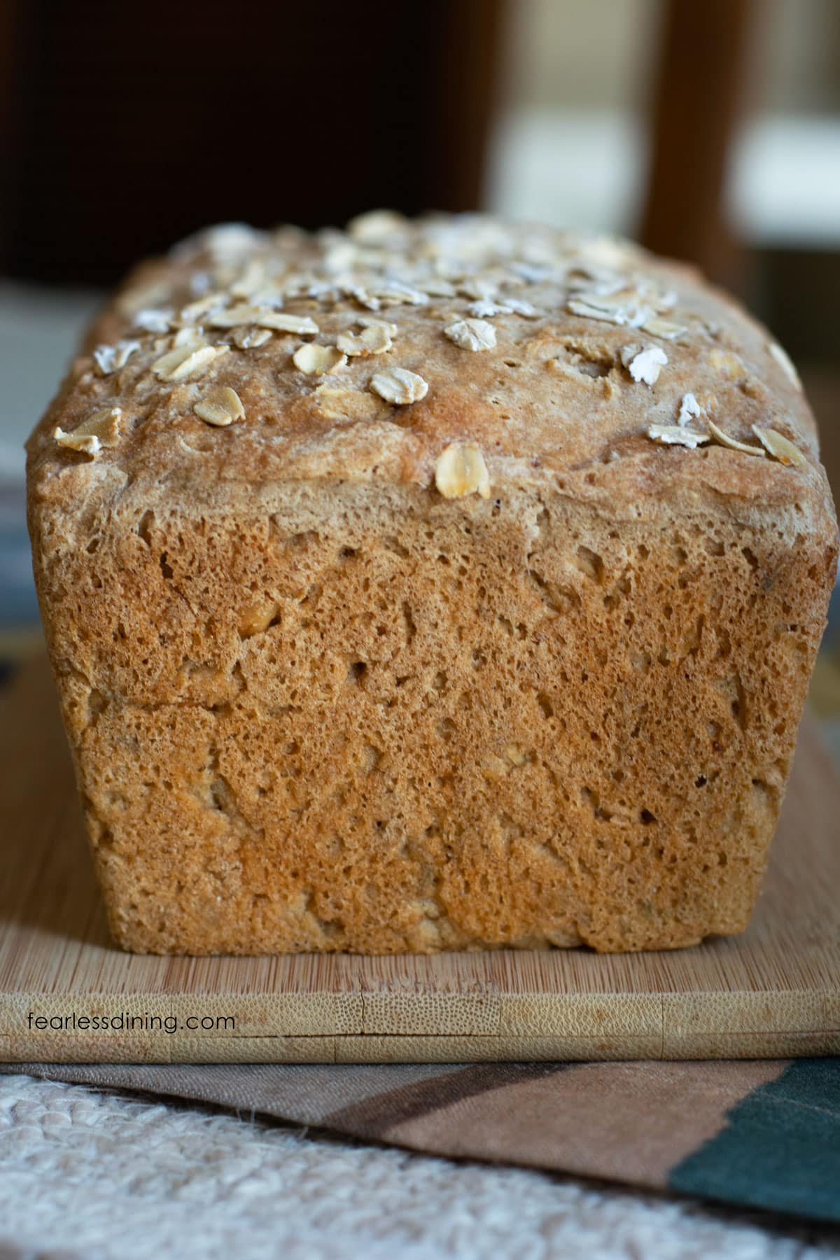 The front view of an unsliced loaf of gluten free oat bread on a cutting board.