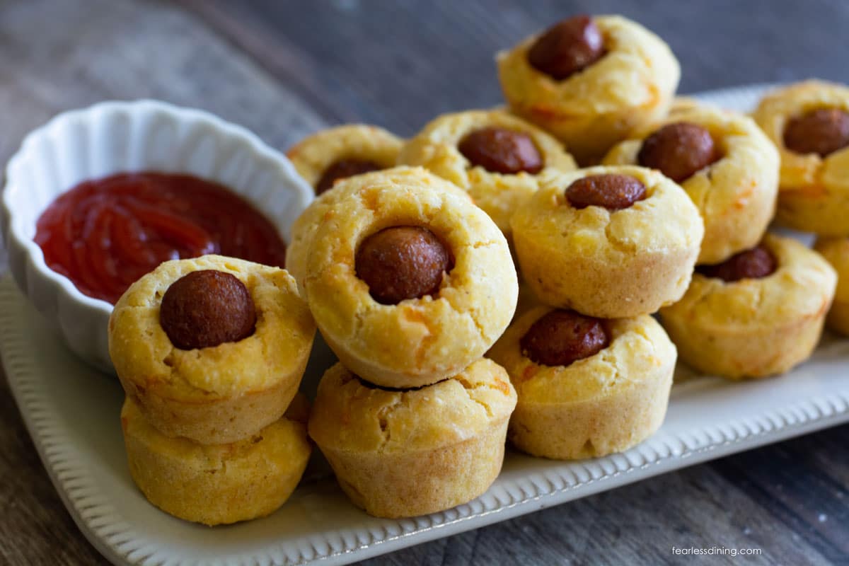 Mini corn dog muffins stacked on a serving platter.