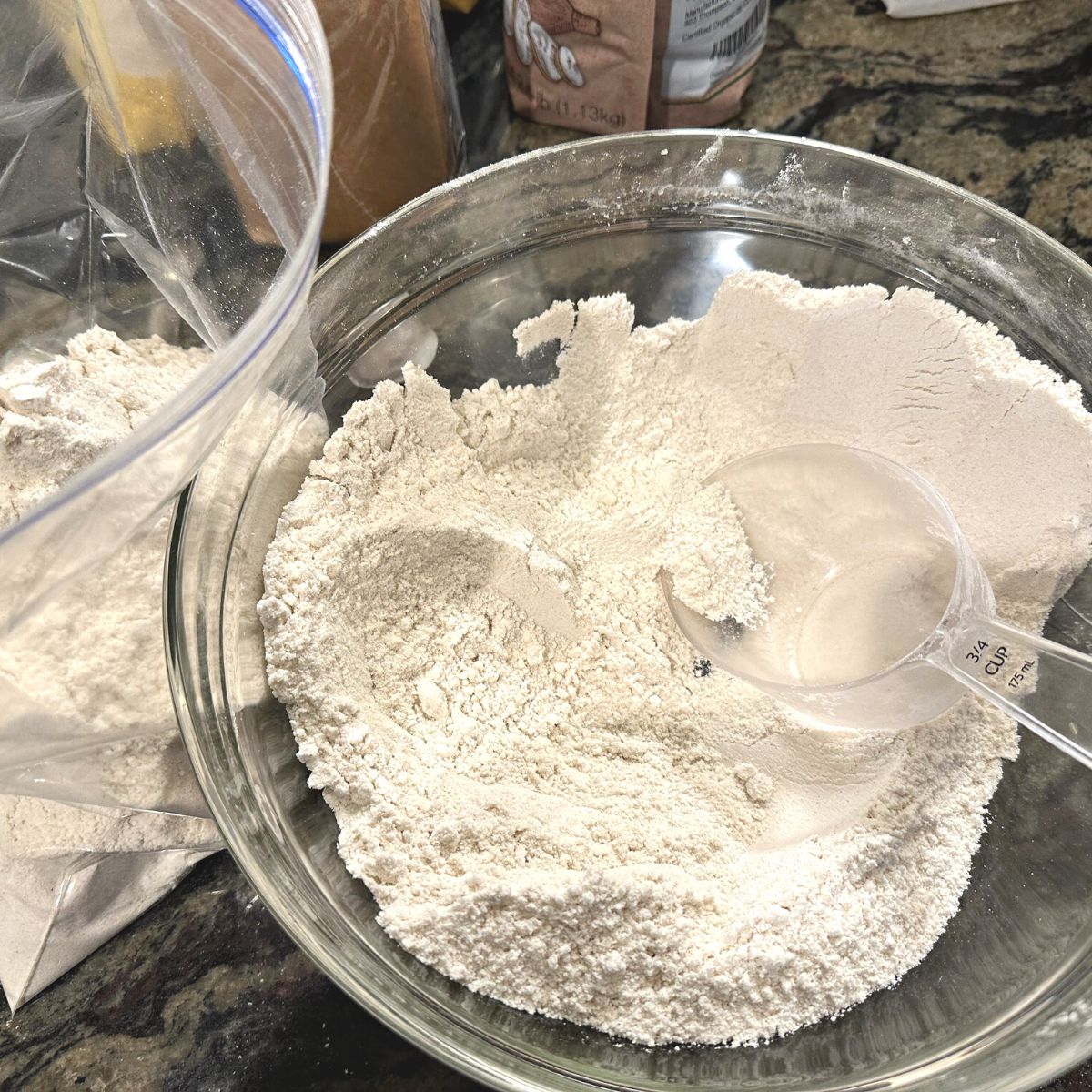 Mixed gluten free flour in a bowl. It has a plastic measuring scoop in the bowl.