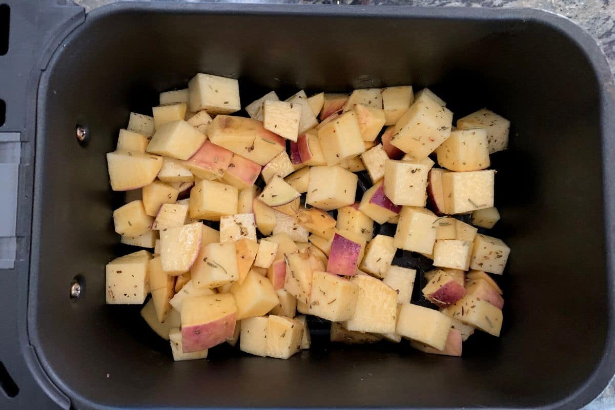 Seasoned rutabaga cubes in the air fryer basket.
