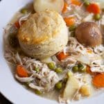 A plate of slow cooker chicken pot pie topped with a biscuit.