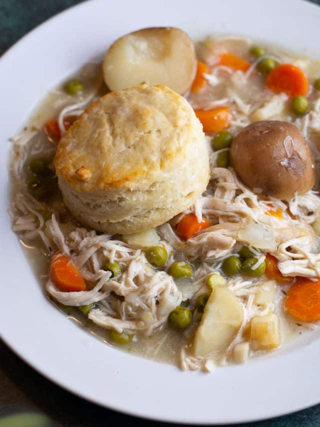 a plate of slow cooker chicken pot pie topped with a biscuit.