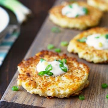 Crispy cauliflower pancakes on a wooden serving platter.