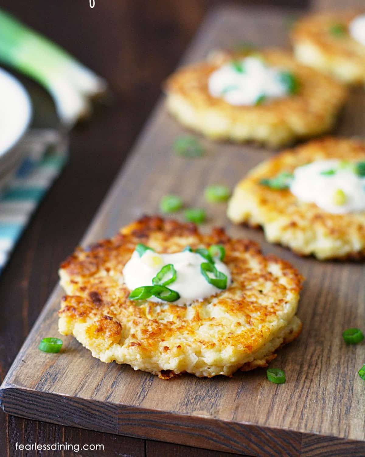 Crispy cauliflower pancakes on a wooden serving platter.