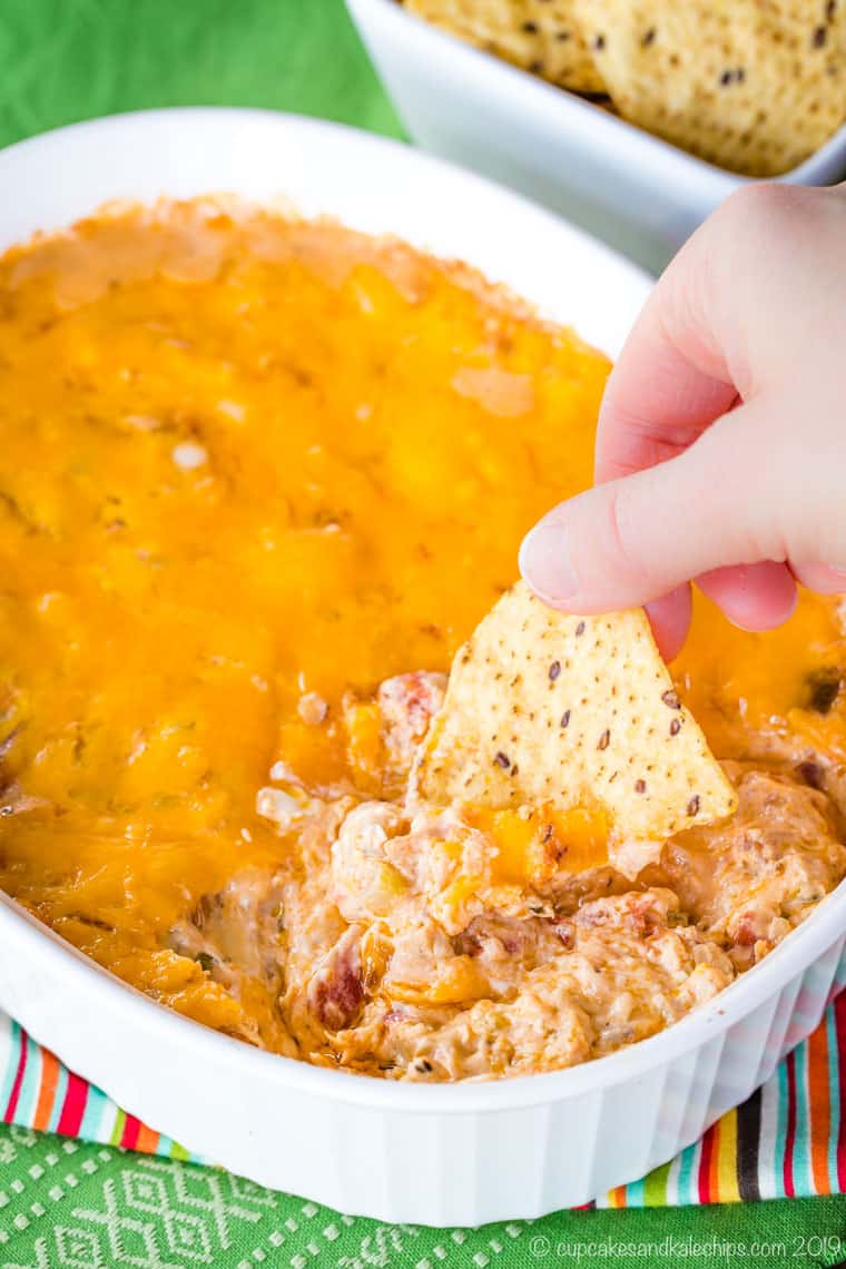 A photo of a hand dipping a chip into the jambalaya dip.