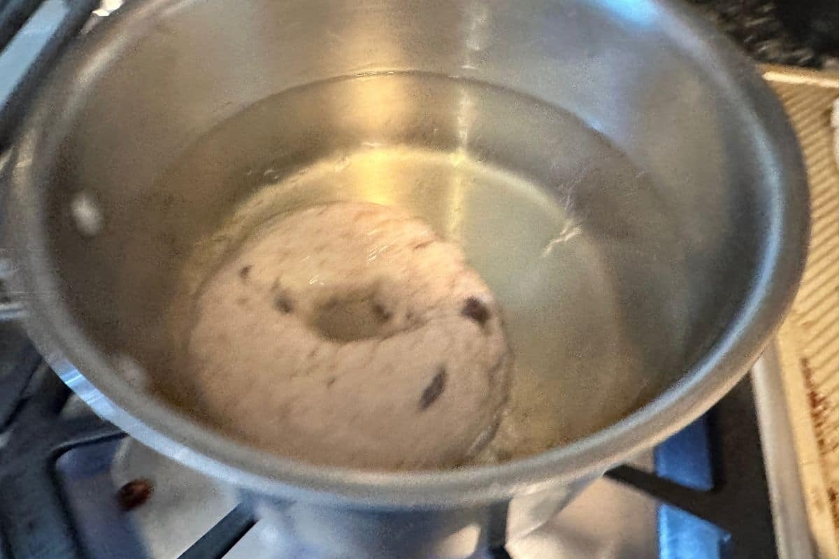 A bagel boiling in a pot of water.