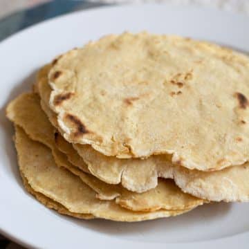 A stack of warm corn tortillas on a plate.