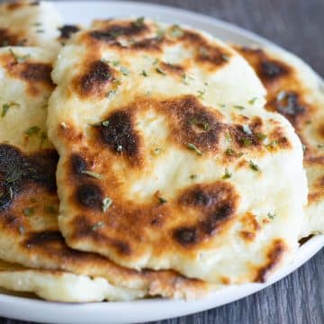 A photo of several pieces of gluten free naan on a white plate.