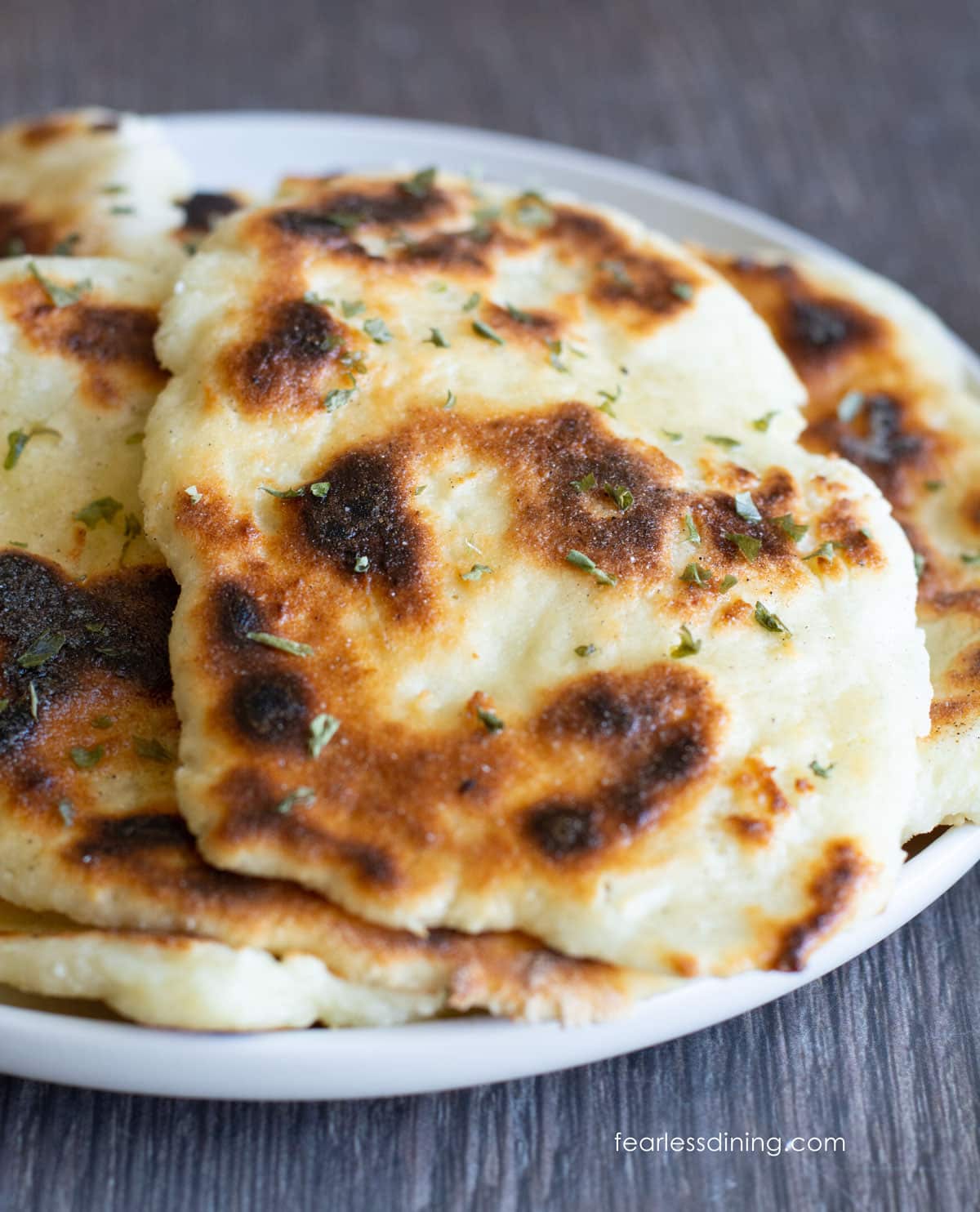 A photo of several pieces of gluten free naan on a white plate.