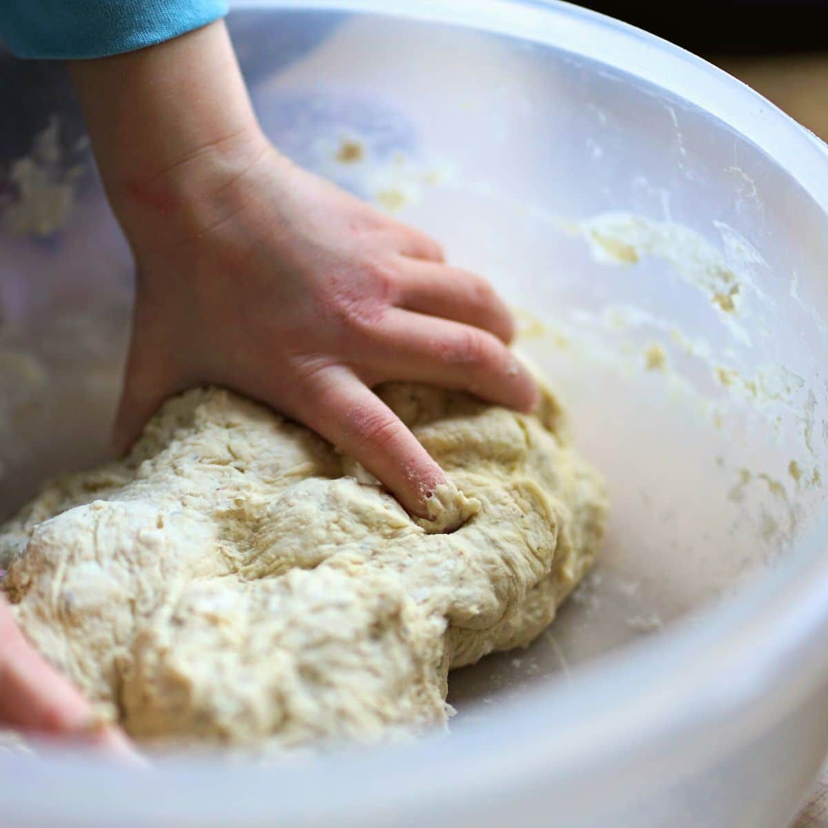 A photo of a little kid's hands kneading dough.