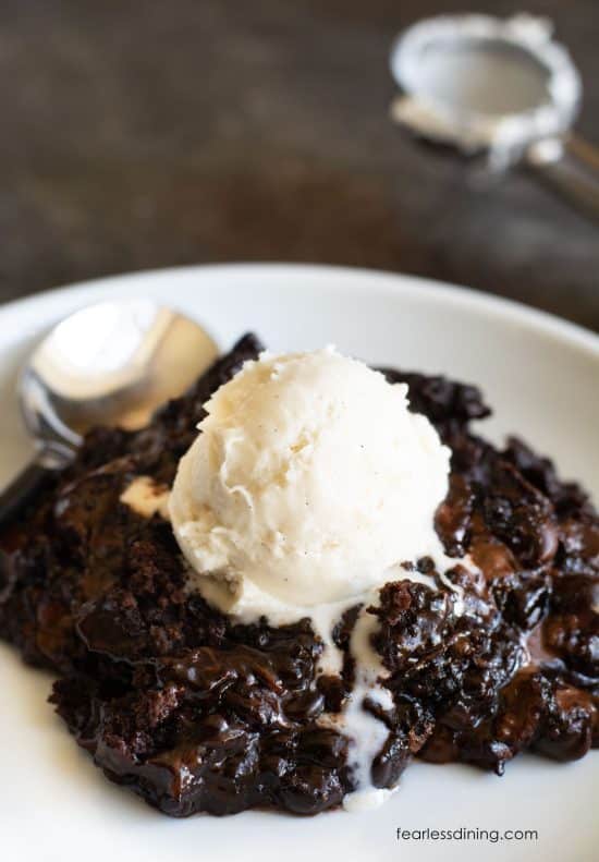 A plate with chocolate lava cake. It is topped with a scoop of vanilla ice cream.