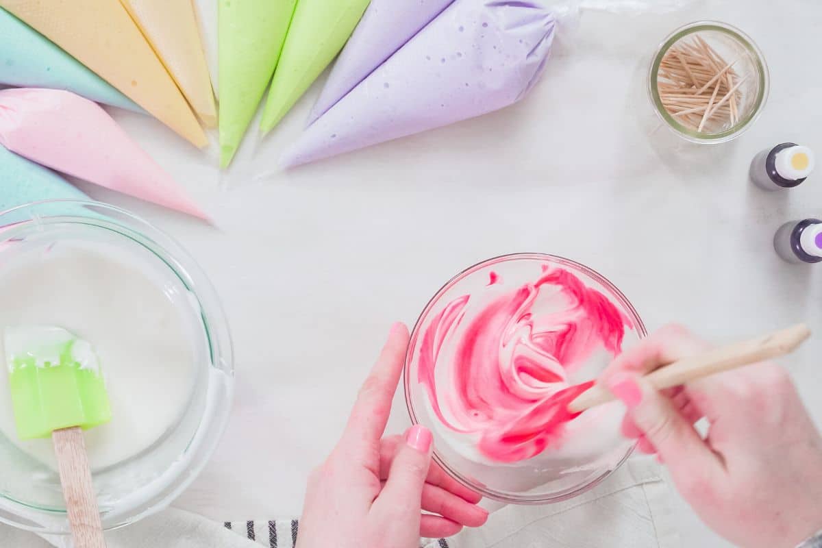 Stirring hot pink food coloring into a small bowl of royal icing.