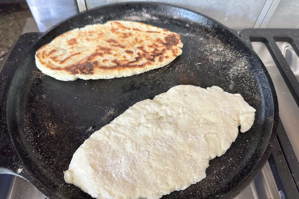 Cooking naan on a hot cast iron skillet.