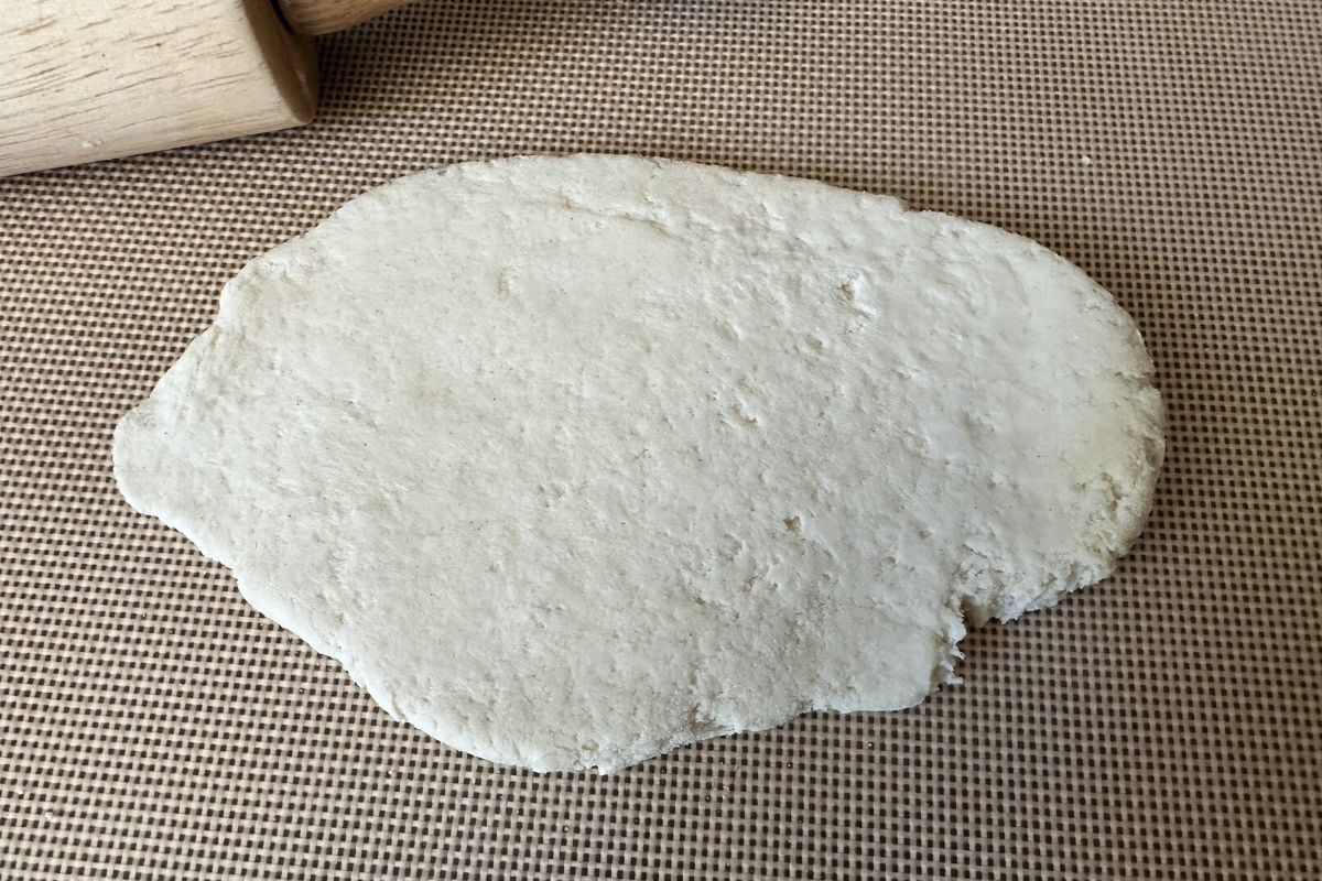 A rolled piece of gluten free naan dough on a silicone mat.