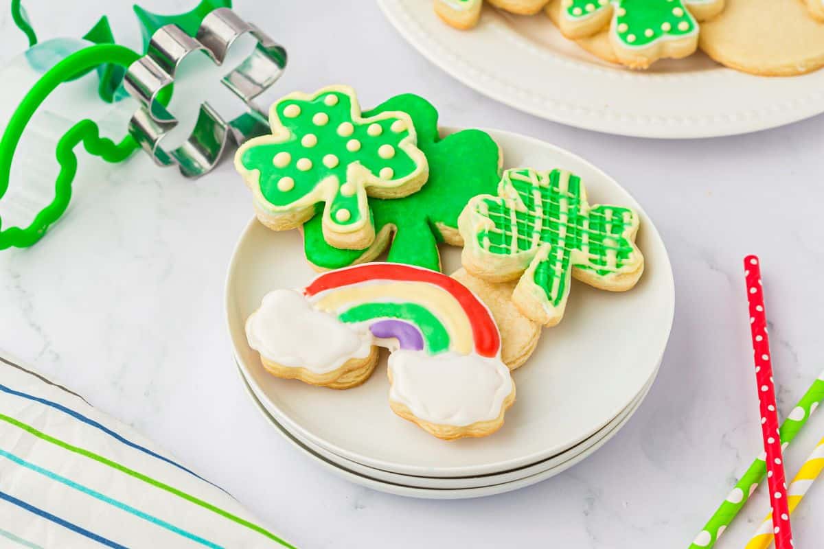 A plate filled with shamrock and rainbow cloud cookes.