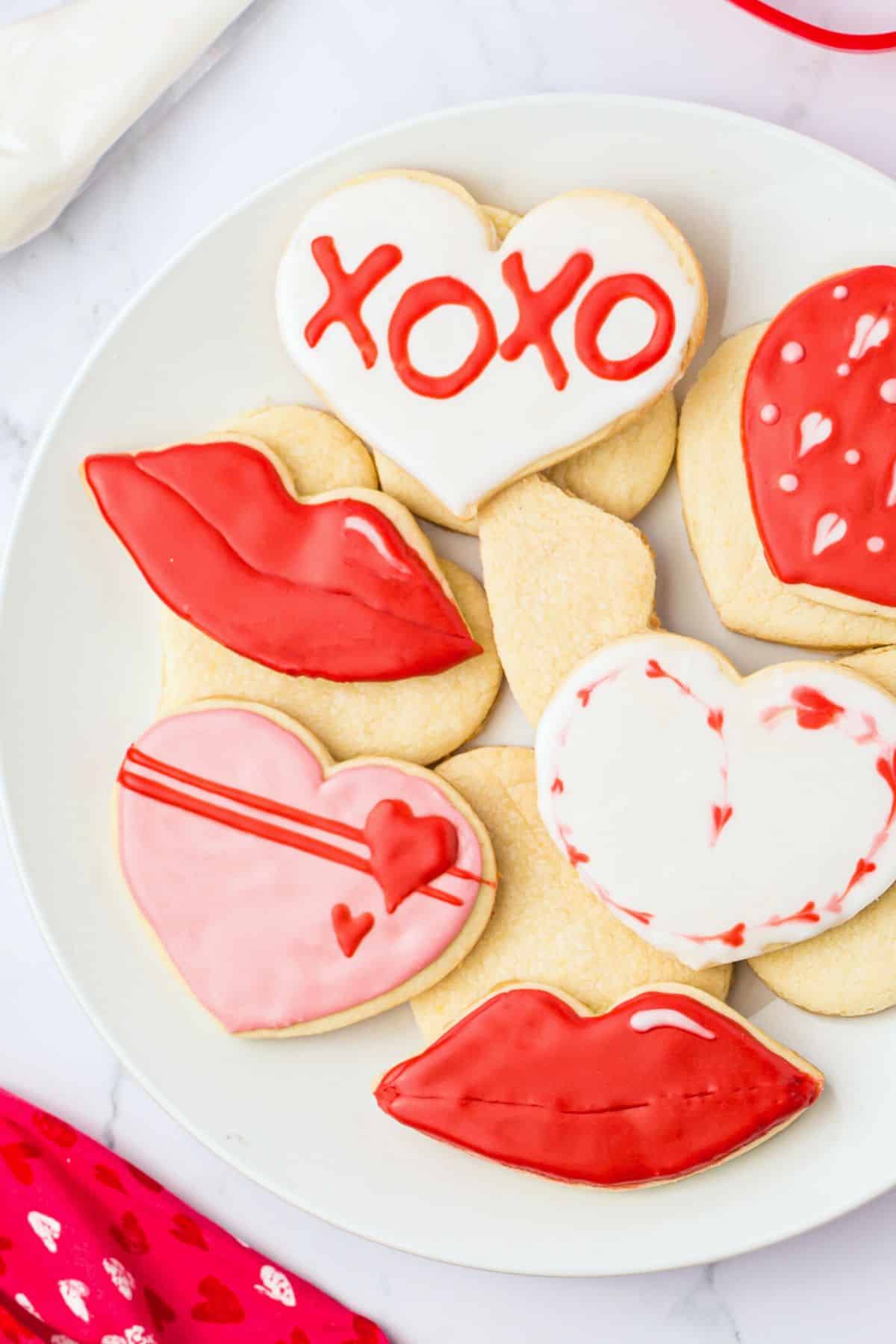 A white plate filled with decorated gluten free valentine's cookies.