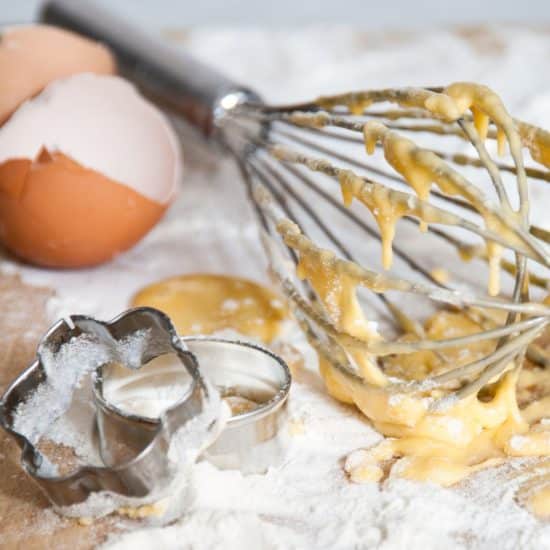 A whisk and other cookie making tools on the counter.