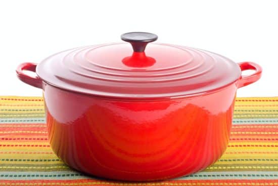 A red Dutch oven on a tablecloth.