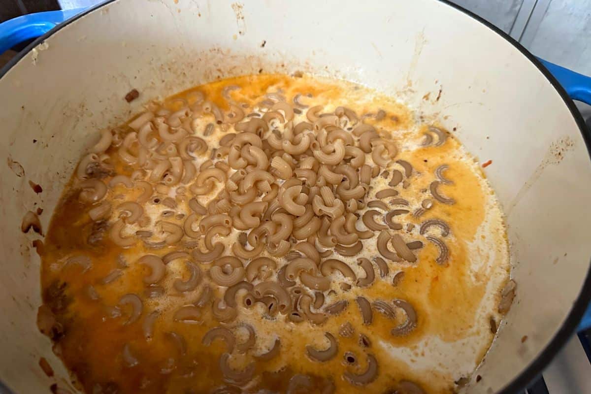 Adding the gluten free elbow macaroni to the pot.