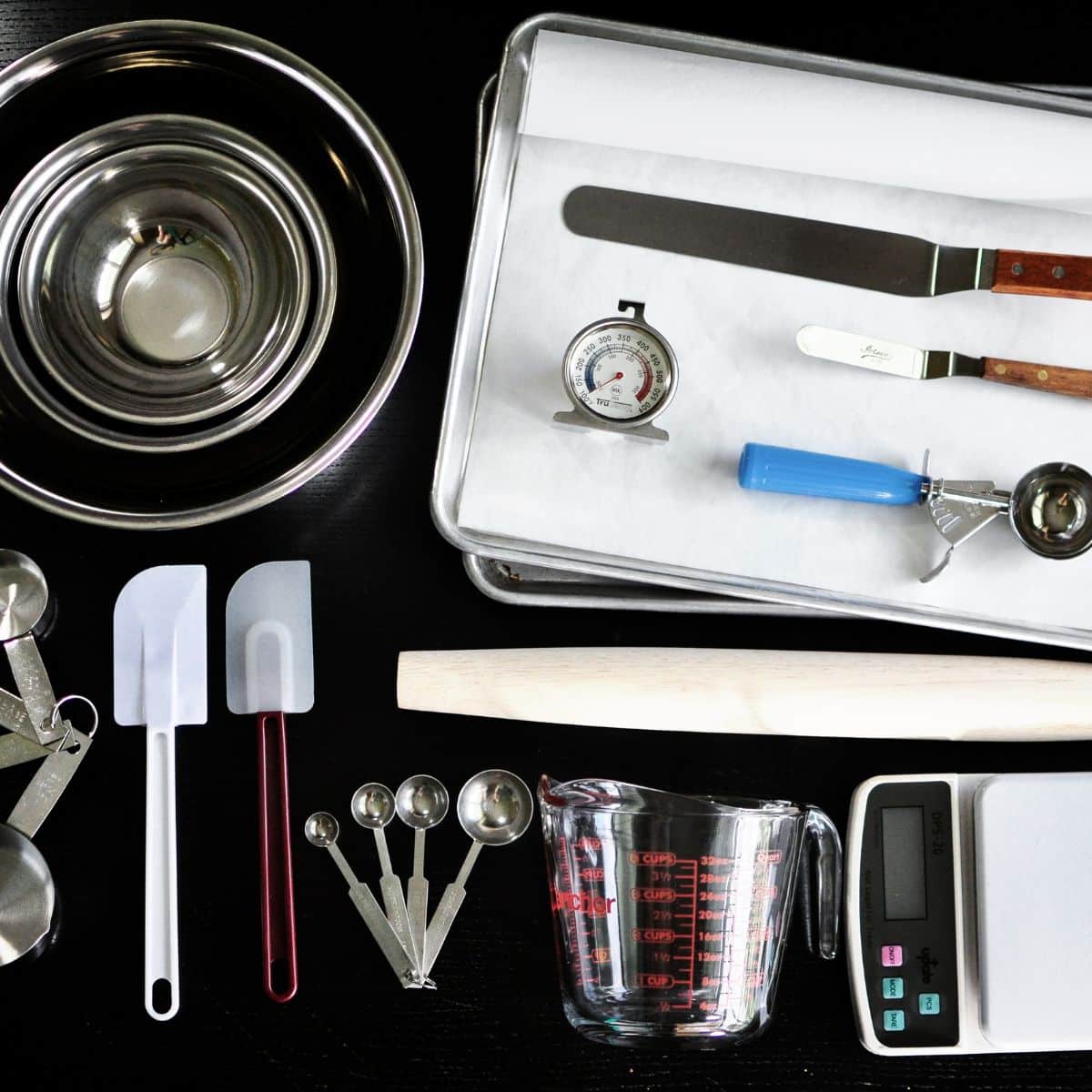 Some kitchen baking tools on a black granite counter.