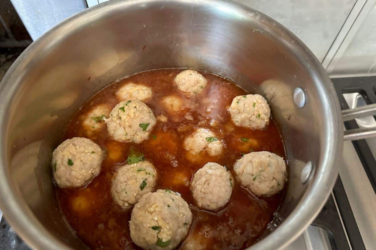 Adding the raw meatballs to the cooking sauce.