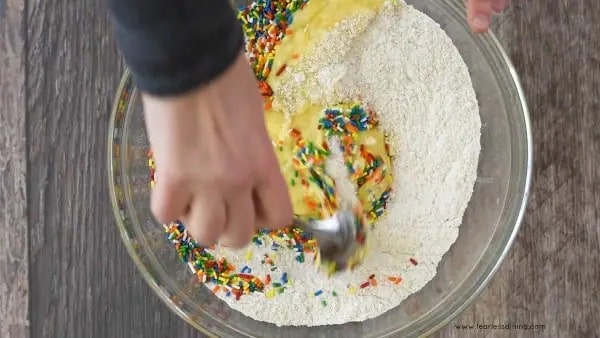 Mixing the wet and dry ingredients together with the rainbow sprinkles.