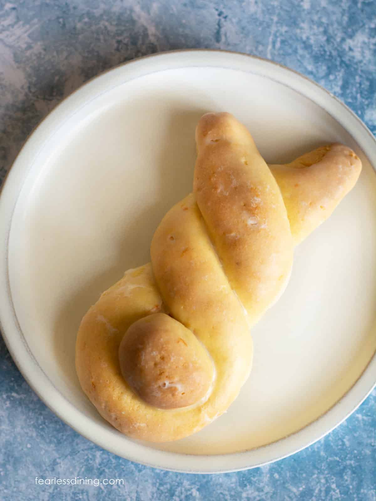 A close up of an orange bunny roll on a white plate.