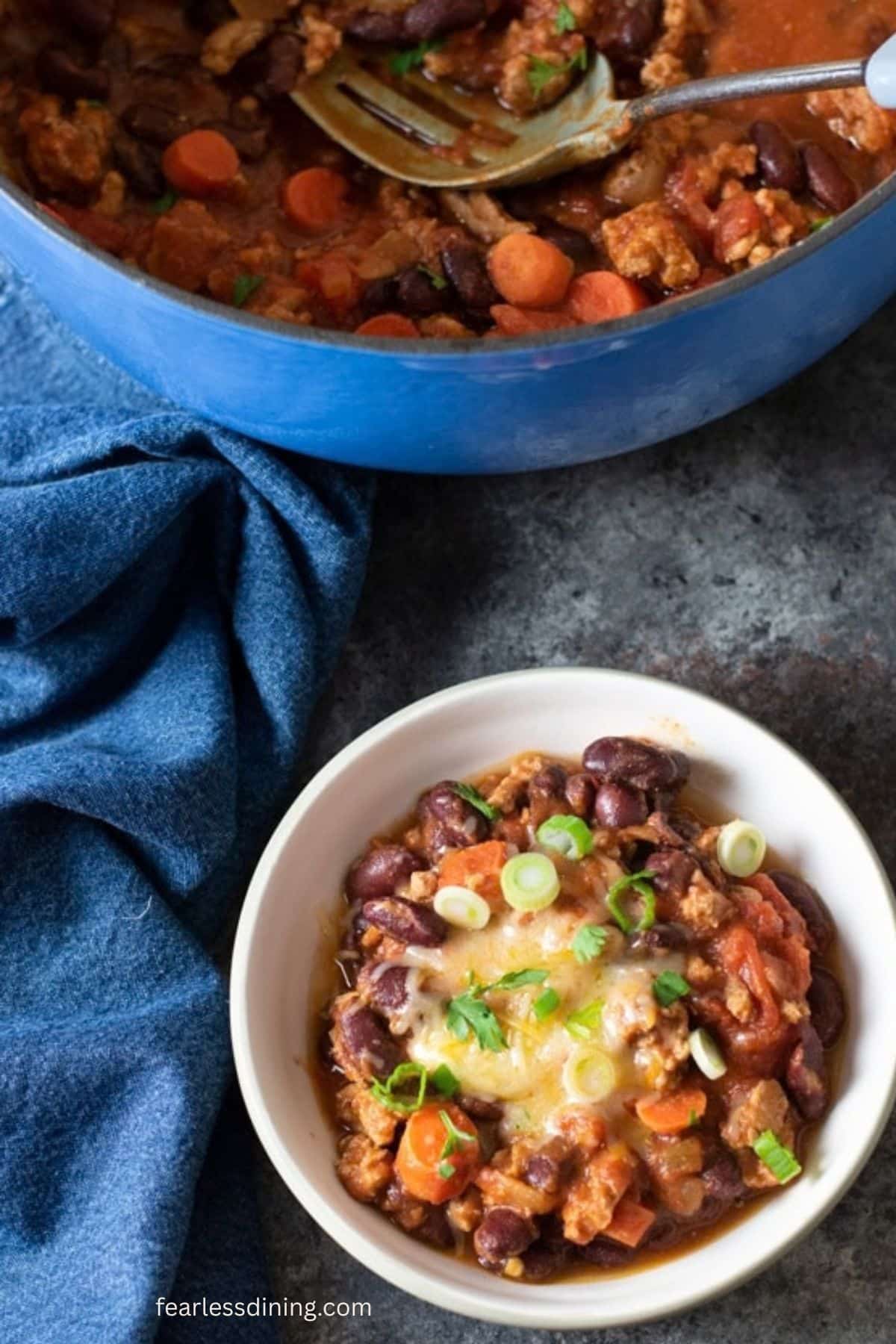 The top view of a bowl of the chili. It is garnished with melted cheddar and scallions.