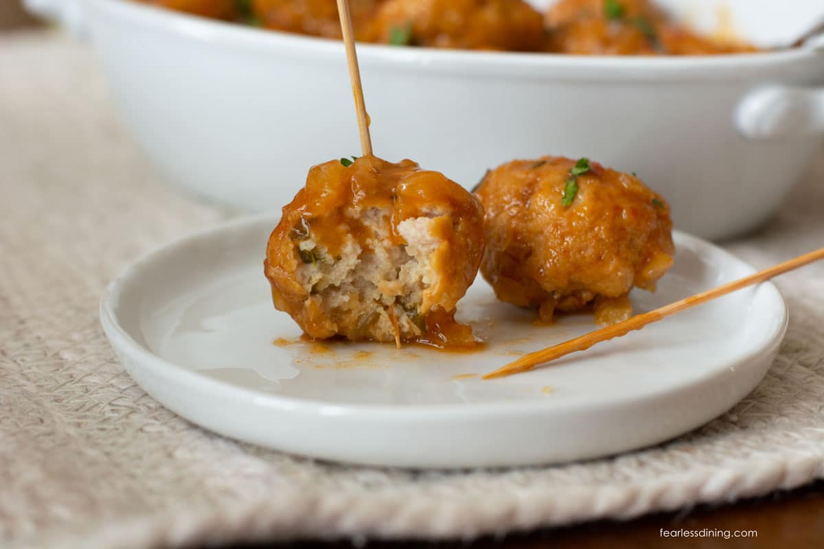 Two meatballs on a small white plate.