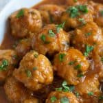 A white serving dish filled with sweet and sour meatballs.