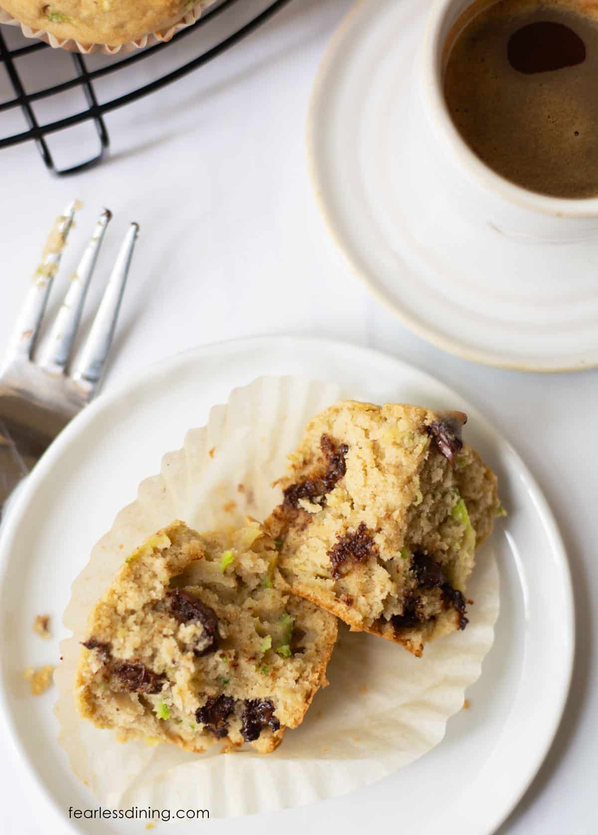 A gluten-free zucchini muffin cut in half on a plate.