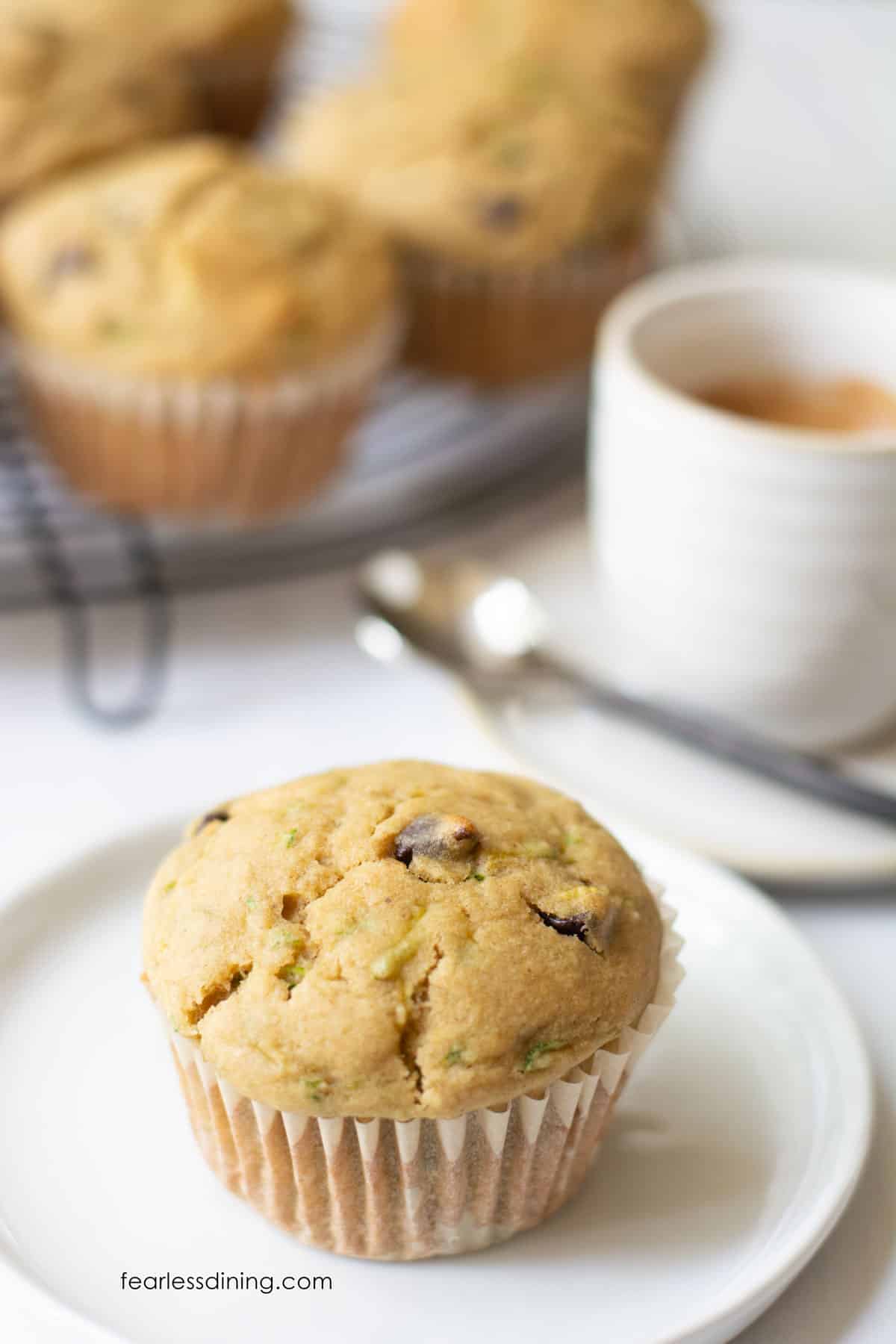 A gluten-free zucchini muffin on a plate next to an espresso.