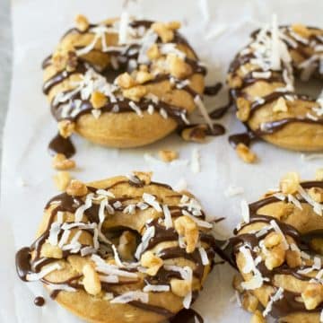 Gluten free banana donuts topped with fudge, coconut, and walnuts.