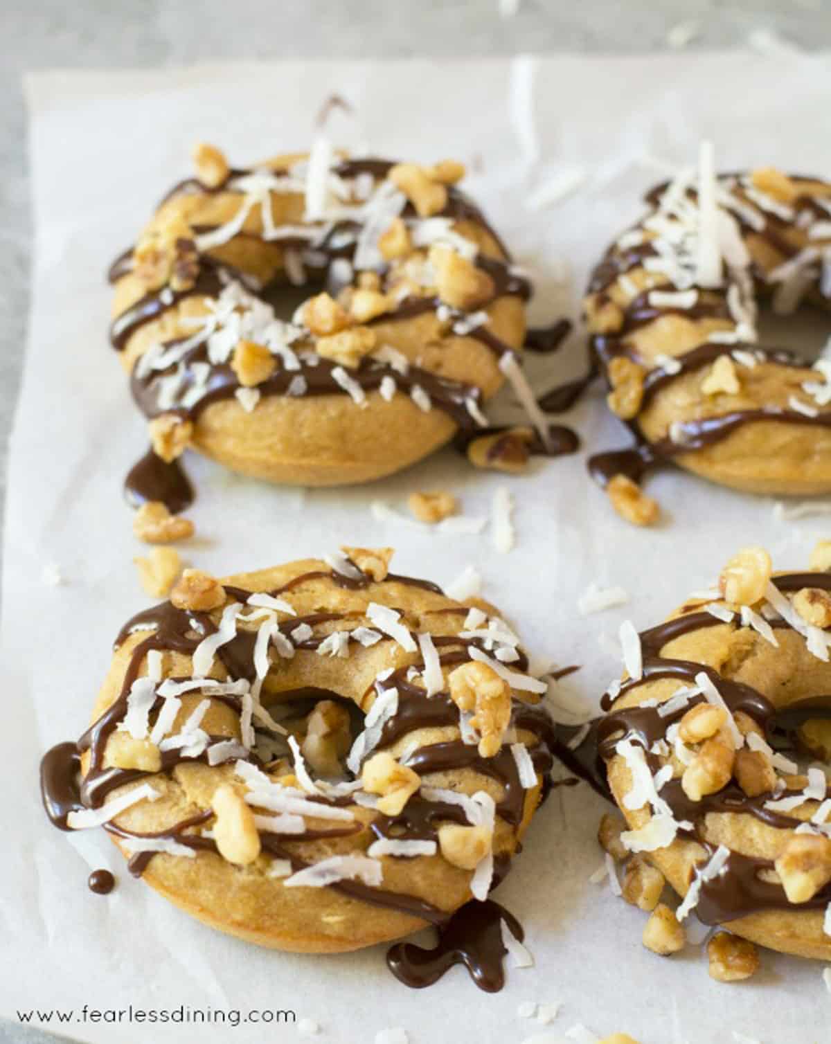 Gluten free banana donuts topped with fudge, coconut, and walnuts.