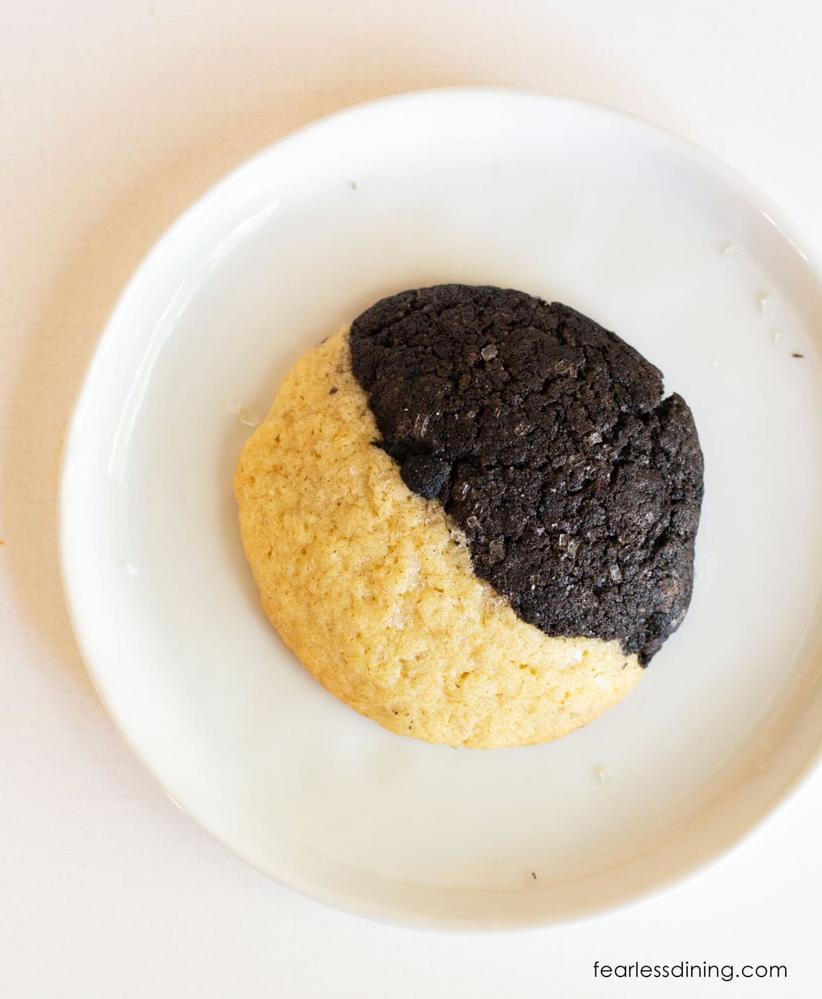 A half chocolate half vanilla cookie on a small white plate.