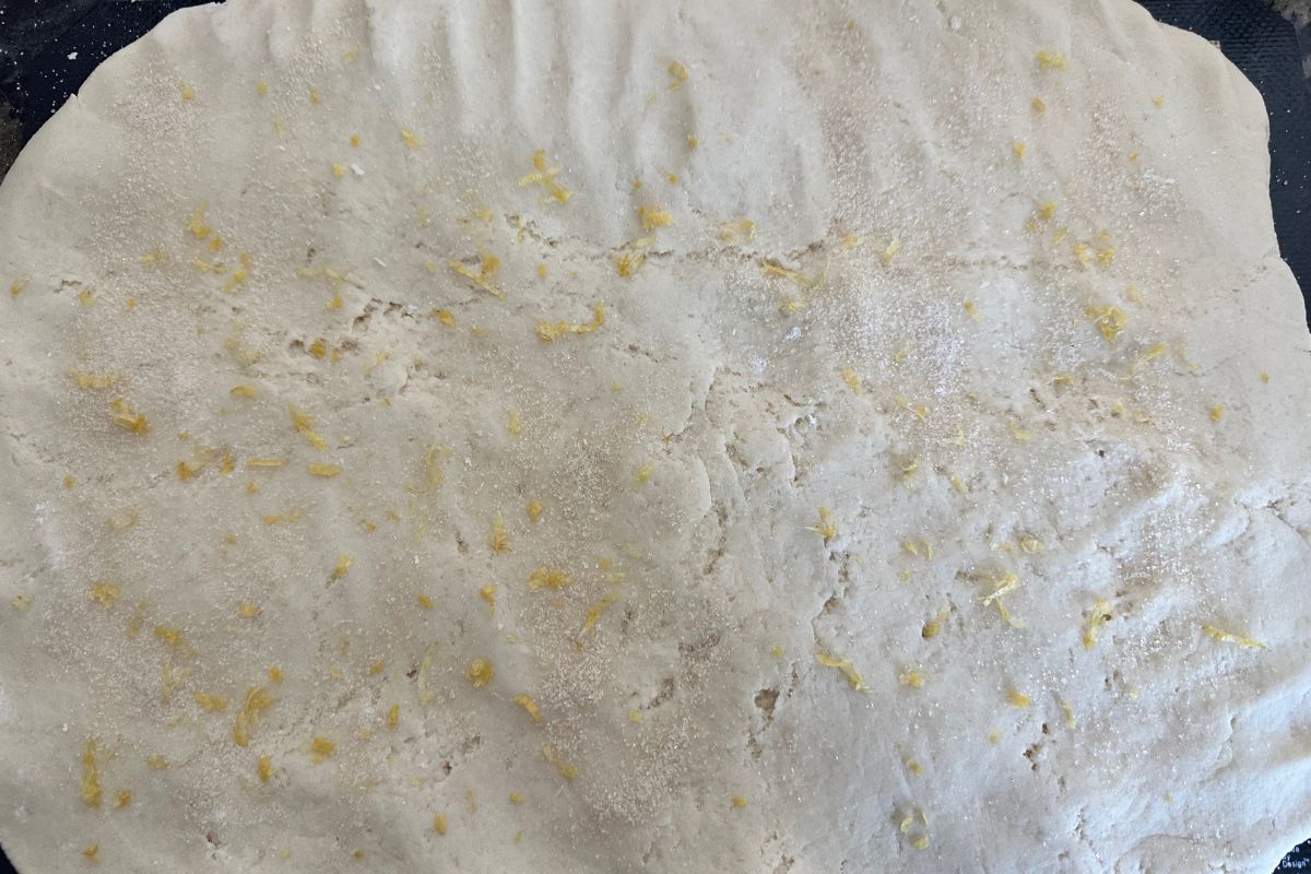 Photo of the dough rolled flat. It has lemon zest and sugar on the dough.