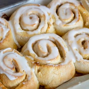 Baked lemon rolls topped with lemonade icing in a pan.
