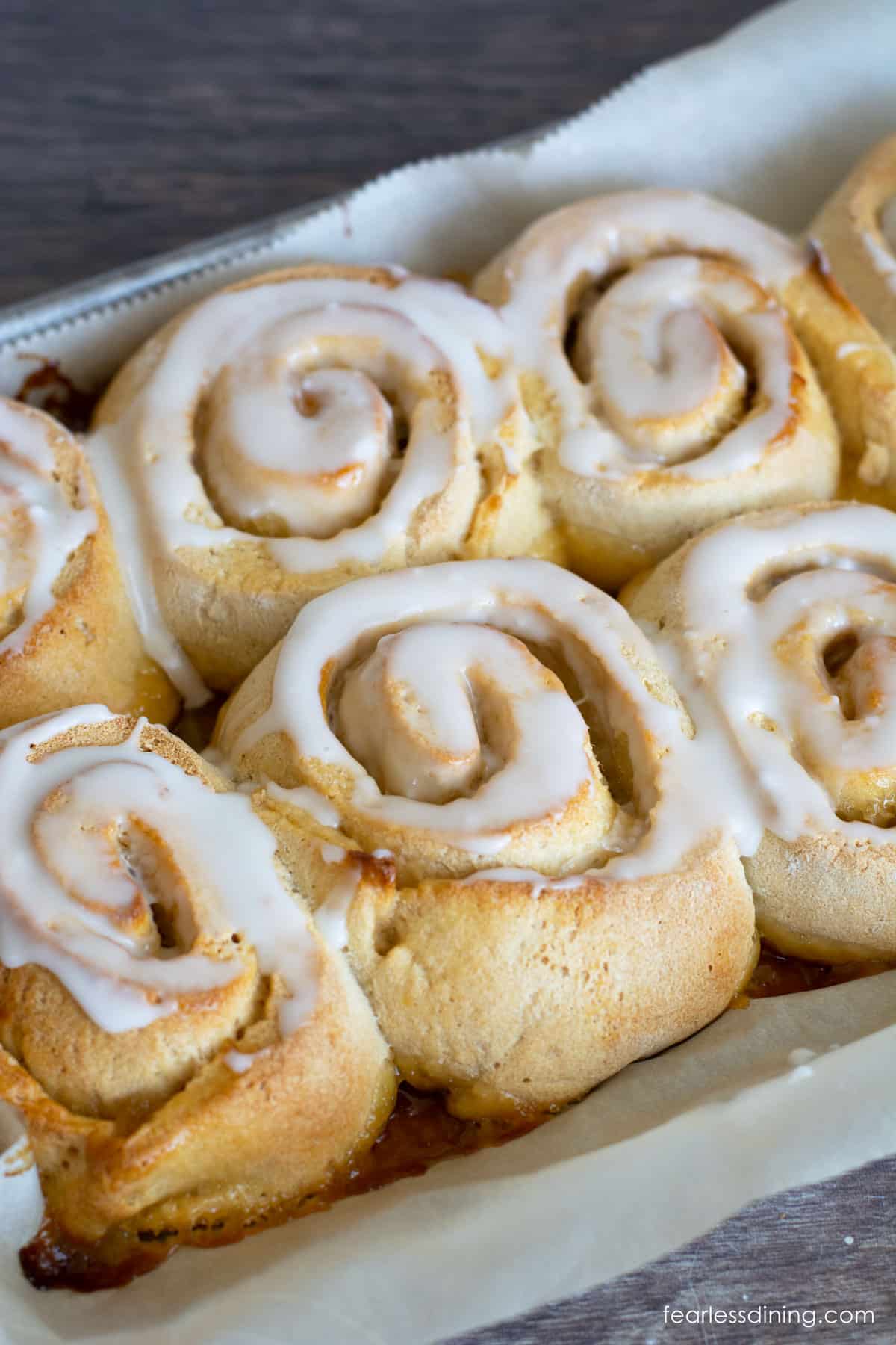 Baked lemon rolls topped with lemonade icing in a pan.