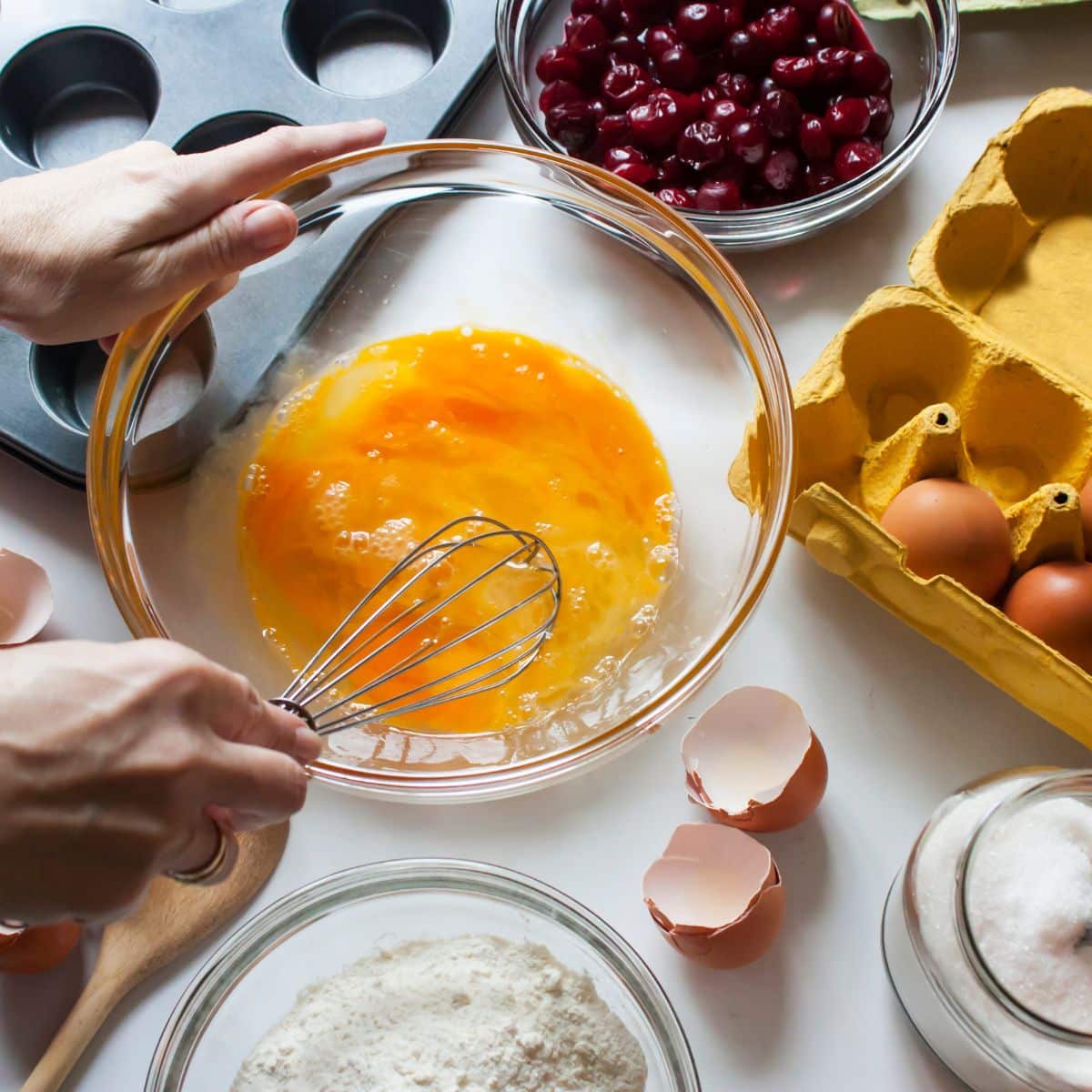 Whisking wet ingredients next to other ingredients and muffin tools.