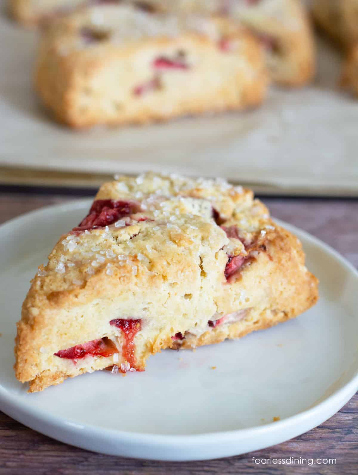 A gluten free strawberries and cream scone on a small white plate.