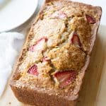 A loaf of gluten free strawberry banana bread on a cutting board.