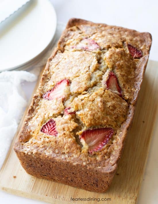 A loaf of strawberry banana bread on a cutting board.