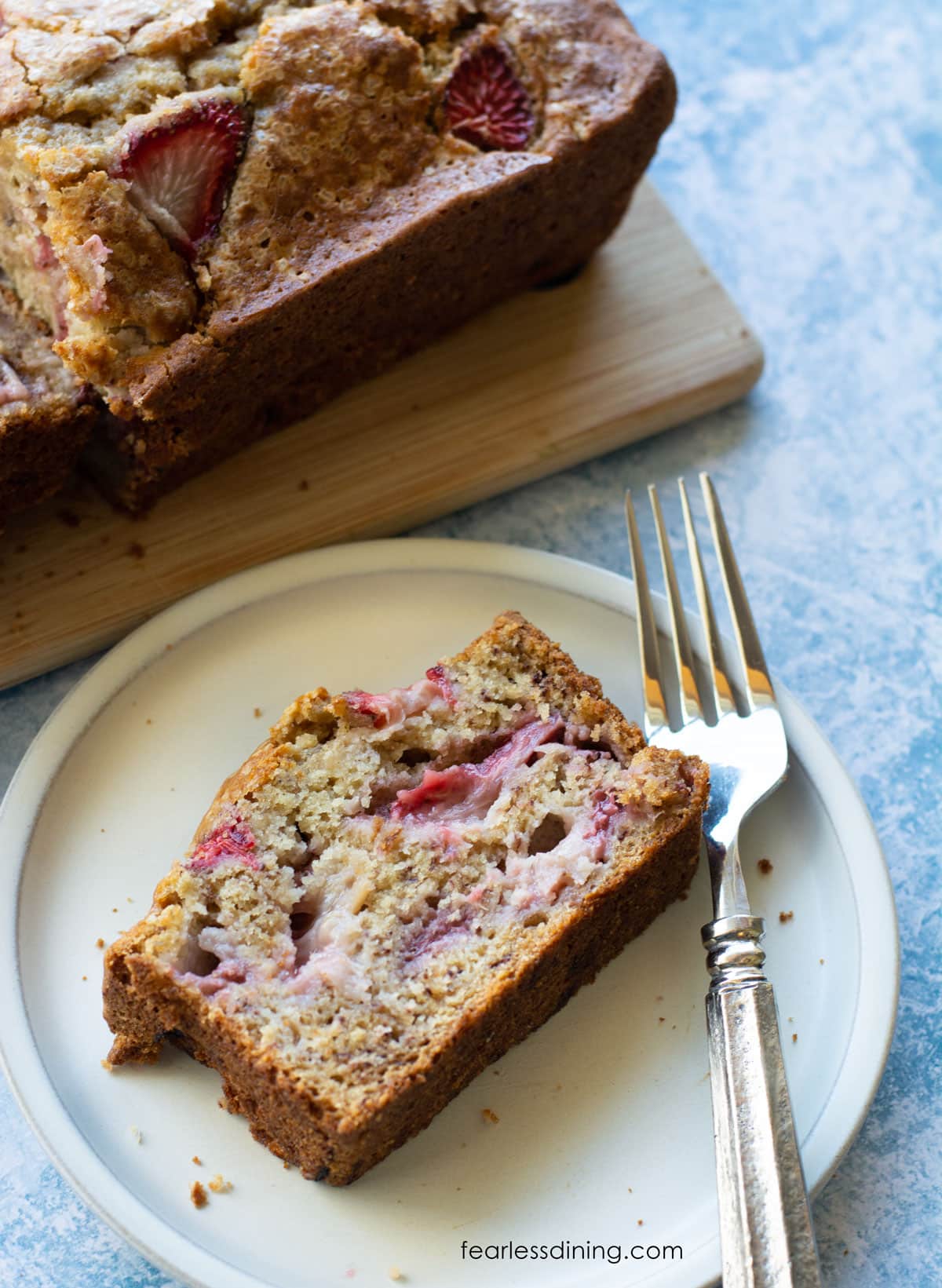 A slice of gluten free strawberry banana bread on a plate with a fork.
