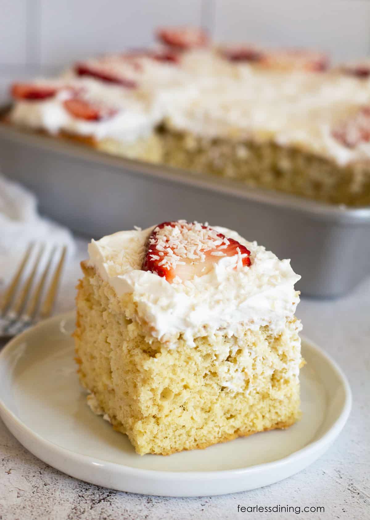 A slice of gluten free tres leches cake on a small white plate.